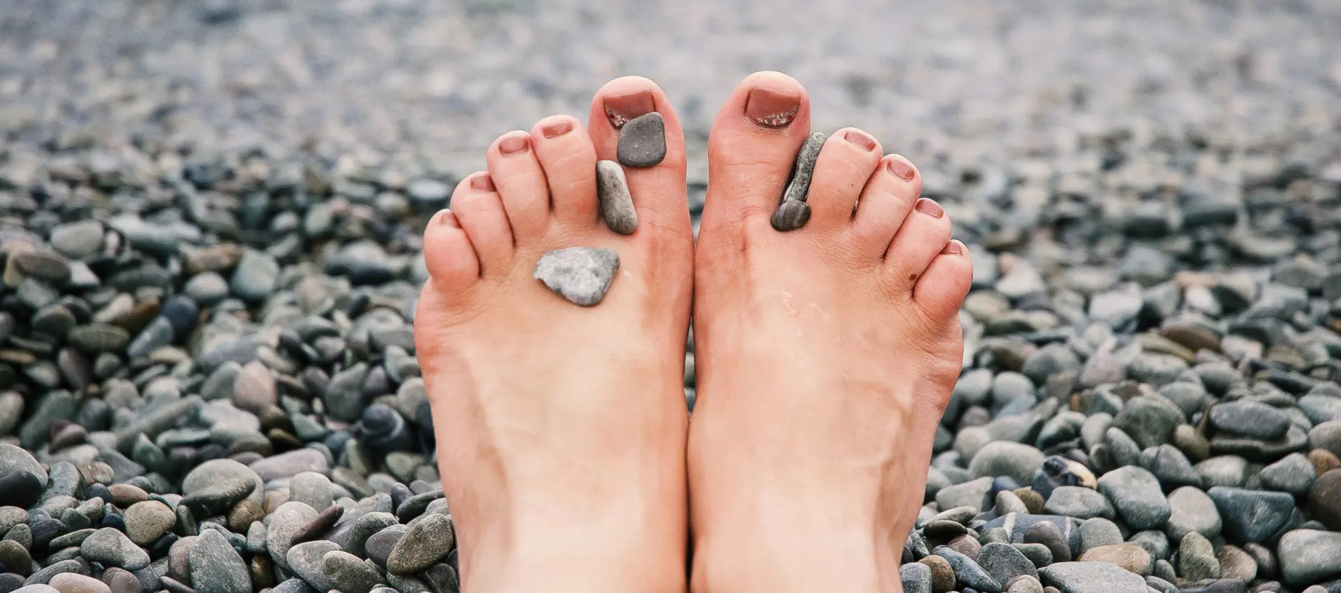 nakte Füße an einem Kieselsteinstrand.