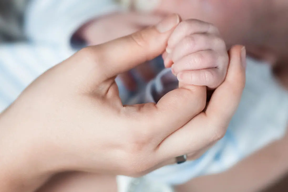 Mamas Hand hält Babys Hand.