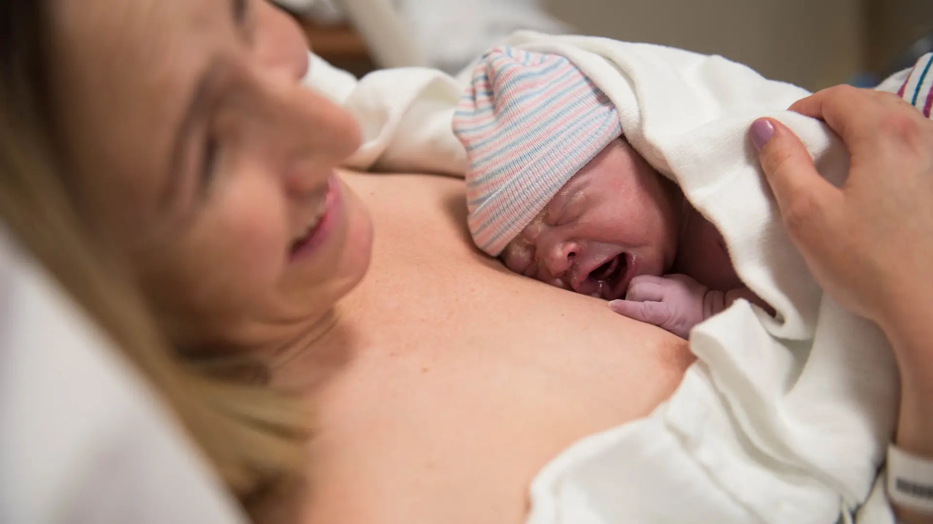 Stolze Mutter mit neugeborenem Kind auf der Brust