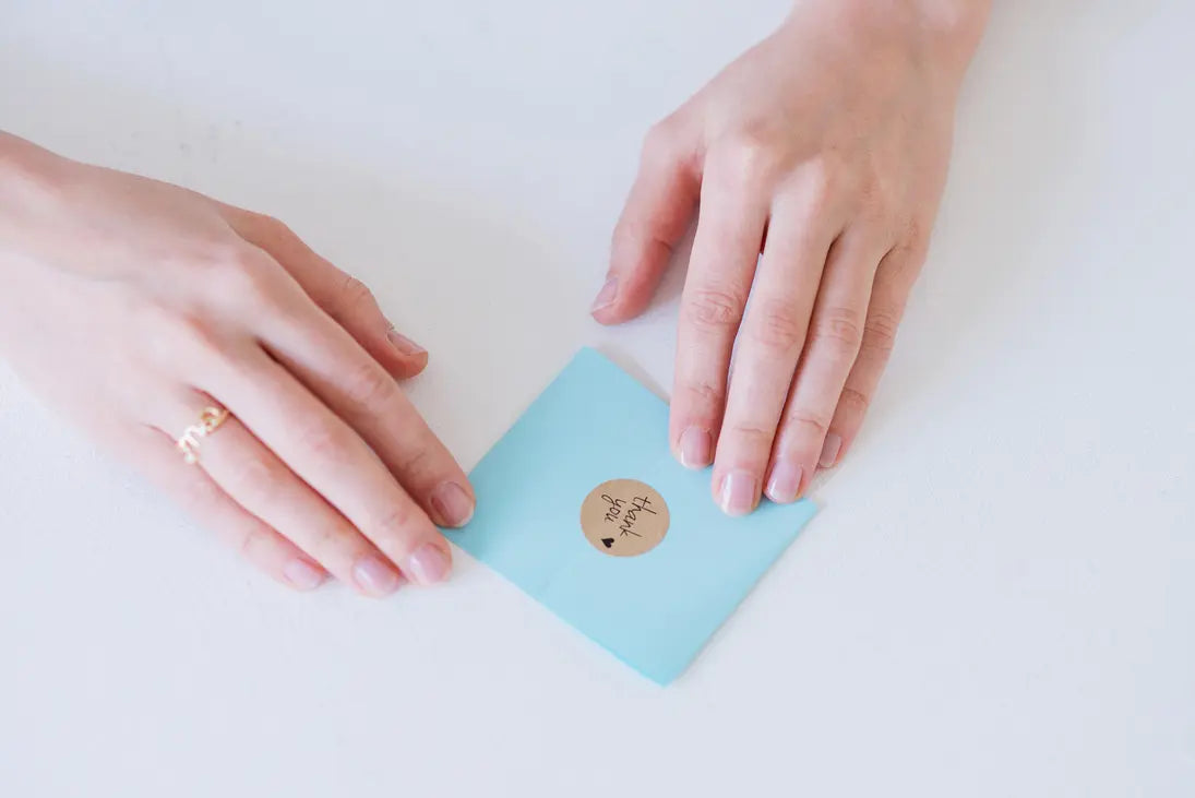 Kleiner blauer Briefumschlag mit thank you Aufkleber und Händen