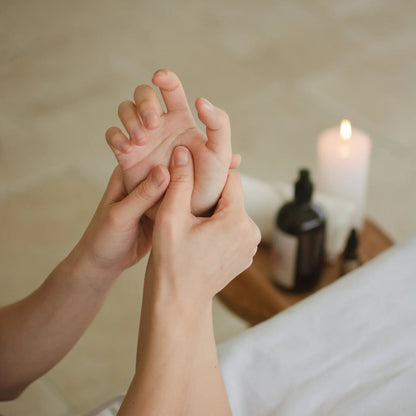 Handmassagge im Hintergrund Kerze und Spenderflasche 