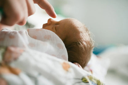 stubst ein Baby an die Nase mit einem Finger